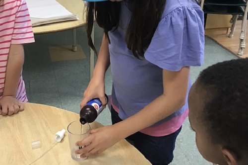 Child pouring hydrogen peroxide into a cup