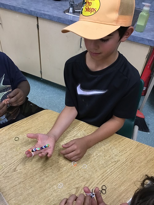 CHild creating with rainbow loom materials. 