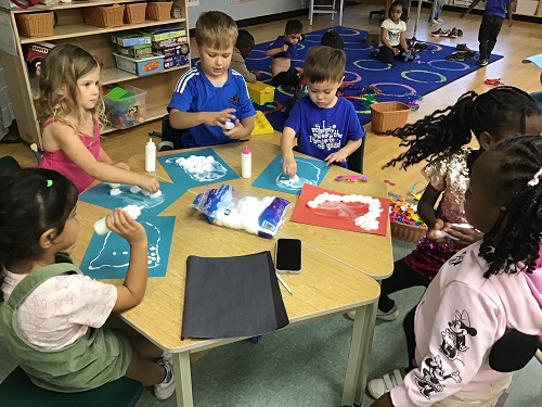Children creating craft ghosts with cotton balls and glue. 