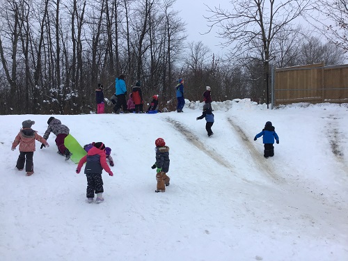 Children sledding on the back of the school hill.