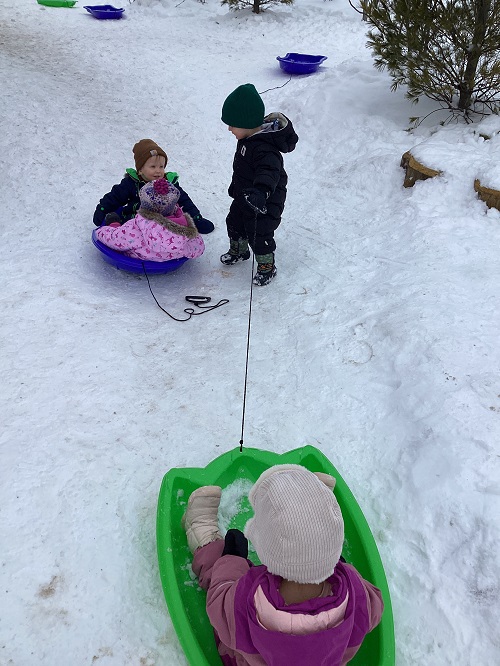 Child pulling friends on a sled.