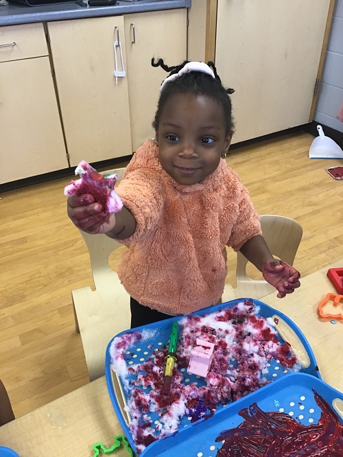 Child showing coloured snow.
