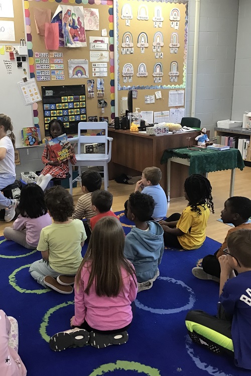 Child reading a story to a group of peers.