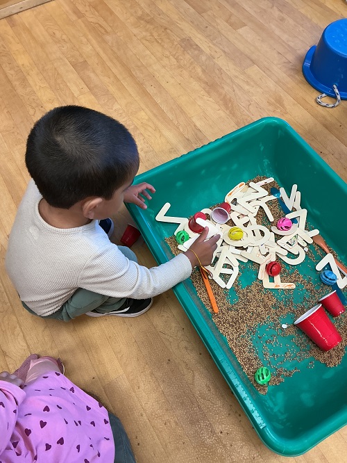 Child explring wooden alphabet letters.