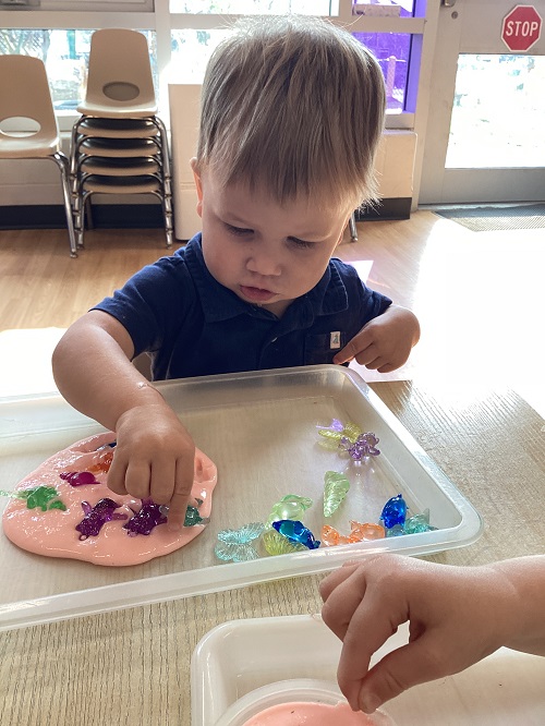 A toddler child playing with gems and slime