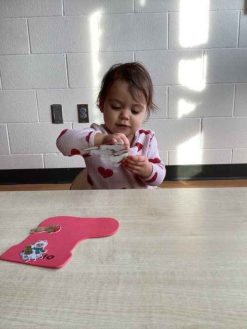 A child exploring with stickers and a paper stocking.