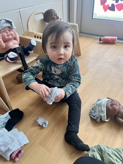 An infant child trying to put on a sock