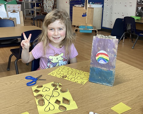 A school age child proudly showing off her chip bag