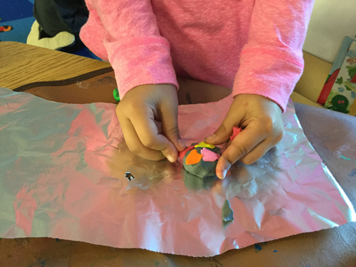 girl making a rock with play dough