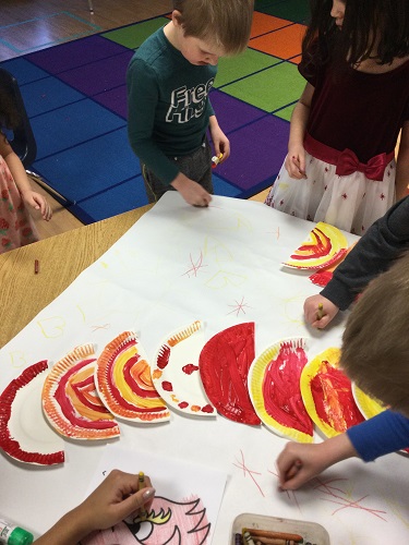 A group of children creating a dragon from paper plates