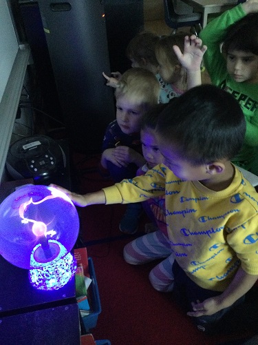 A group of children looking at a plasma globe
