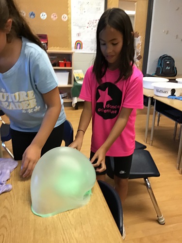 Child made a lage green bubble with slime 