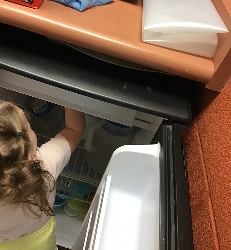 An infant getting items from a fridge