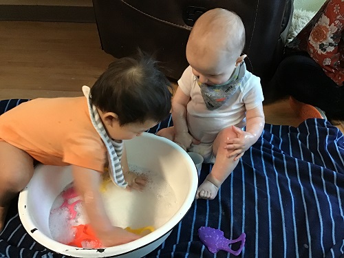Infants playing in with a container of water