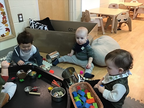 Three infants exploring with blocks, corks and other items
