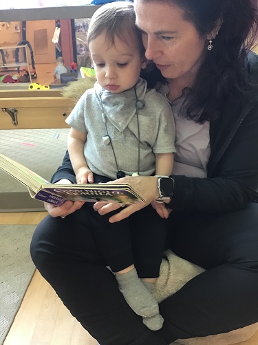 An infant reading with an educator