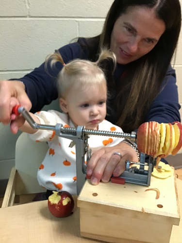 A child and educator peeling apples