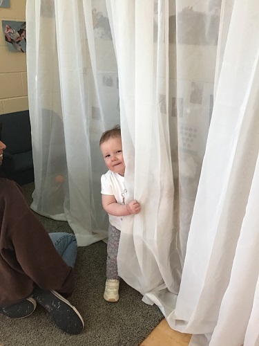 A child hiding behind a drape