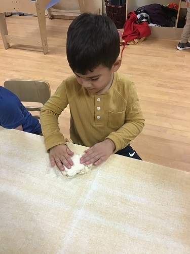 A child forming his salt dough into a diva lamp