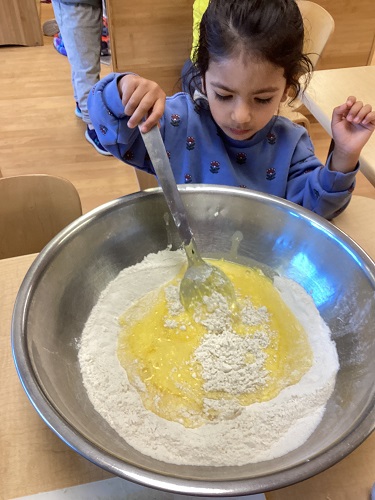 A child stirring a big bowl of flour for making muffins