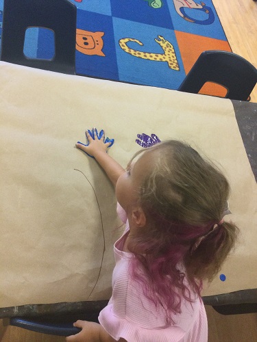 A child adding handprints to paper