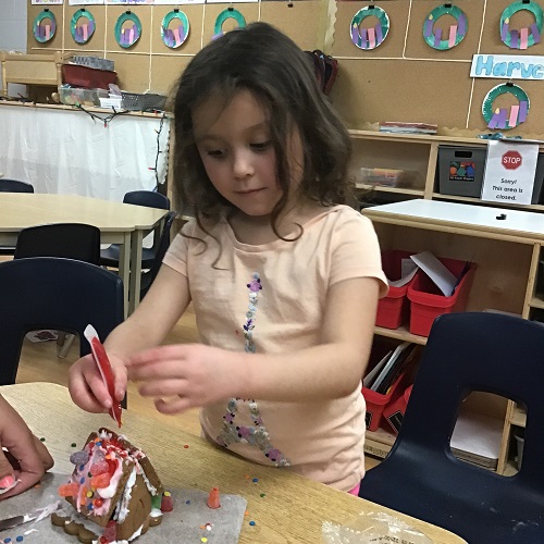 A child putting icing on a gingerbread house