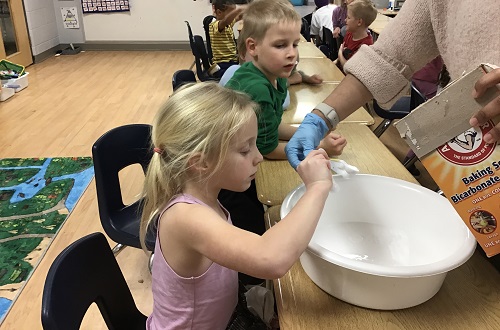 Children measuring ingredients together to make slime