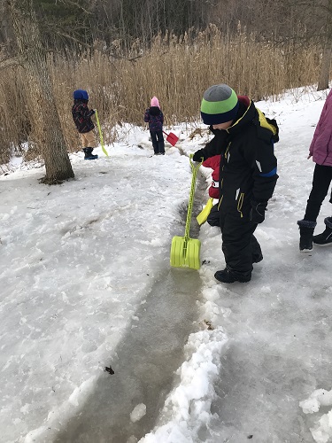 Children digging a passage in the snow for water to flow down