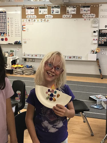 A child holding up their completed Diya