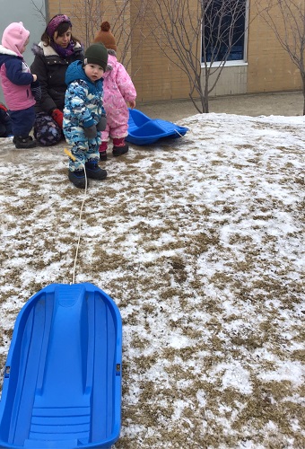 A child pulling a sled up the hill