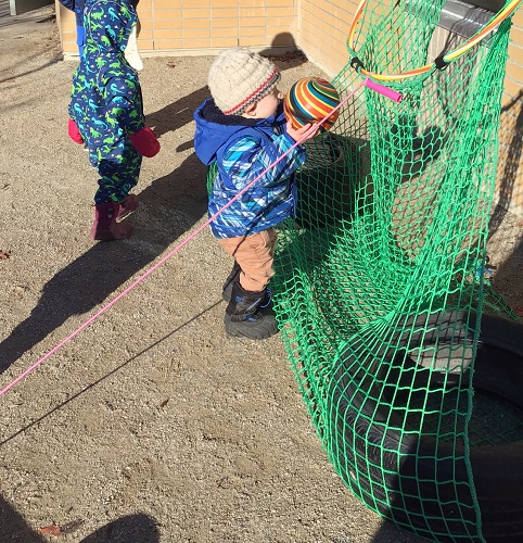 A toddler trying to put a ball into a net