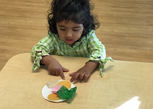 Child gluing tissue paper to paper